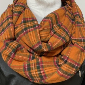 May include: A warm orange, green, and red plaid infinity scarf. The scarf is made of a soft, cozy fabric and is perfect for keeping warm in the colder months.