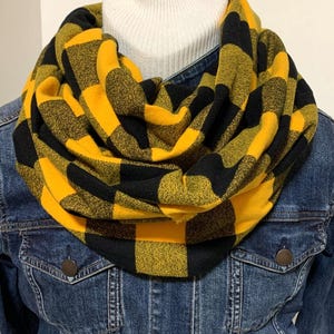 May include: A yellow and black plaid infinity scarf. The scarf is made of a soft, cozy fabric and is perfect for keeping warm in the winter.