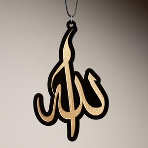 May include: A black and gold car air freshener with the word "Allah" written in Arabic calligraphy.