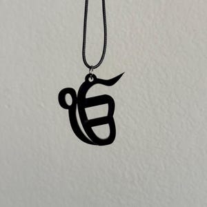 May include: A black pendant necklace with a Khanda symbol, a religious symbol in Sikhism.