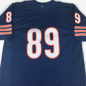 K&ouml;nnte beinhalten: Marineblaues Mesh-Trikot mit wei&szlig;en, orange umrandeten Zahlen. Das Trikot hat die Nummer 89 auf der Vorderseite und die Nummern 8 und 9 auf den &Auml;rmeln. Orange und wei&szlig;e Streifen zieren die &Auml;rmelb&uuml;ndchen.