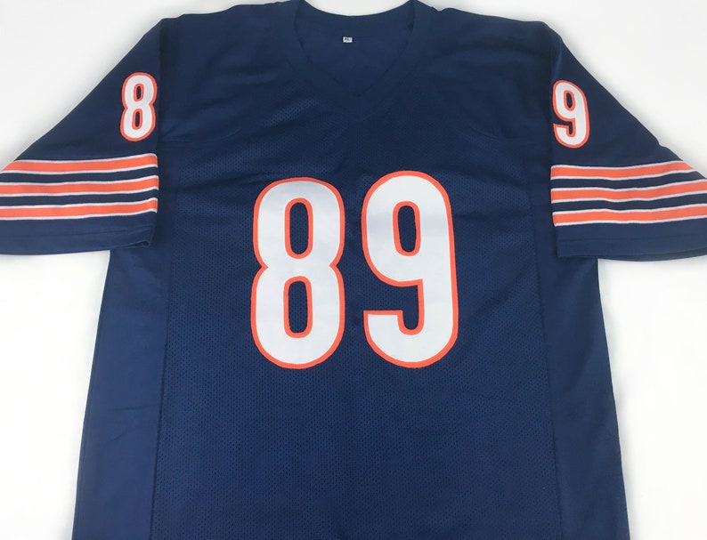 K&ouml;nnte beinhalten: Marineblaues Mesh-Trikot mit wei&szlig;en, orange umrandeten Zahlen. Das Trikot hat die Nummer 89 auf der Vorderseite und die Nummern 8 und 9 auf den &Auml;rmeln. Orange und wei&szlig;e Streifen zieren die &Auml;rmelb&uuml;ndchen.