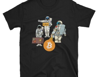 May include: Black t-shirt with a graphic of four astronauts holding luggage and a sign that says "To Moon". A large gold Bitcoin symbol is in the foreground.