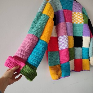 Puede incluir: Un c&aacute;rdigan de crochet colorido con un dise&ntilde;o de patchwork. El c&aacute;rdigan est&aacute; hecho de cuadrados de varios colores, incluyendo rosa, azul, verde, amarillo, rojo y morado.