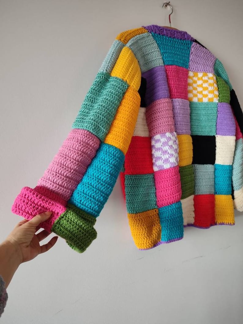 Puede incluir: Un c&aacute;rdigan de crochet colorido con un dise&ntilde;o de patchwork. El c&aacute;rdigan est&aacute; hecho de cuadrados de varios colores, incluyendo rosa, azul, verde, amarillo, rojo y morado.