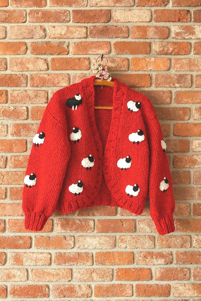 A bright red, open-front cardigan sweater with a sheep pattern. embroidered cardigan inspired from Princess Diana's iconic sweater.