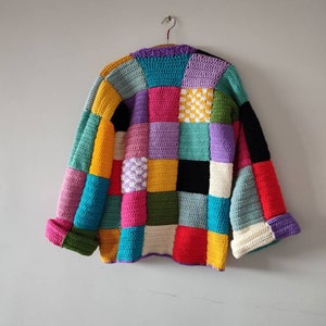 Puede incluir: Un c&aacute;rdigan de crochet colorido con un dise&ntilde;o de patchwork. El c&aacute;rdigan est&aacute; hecho de cuadrados de varios colores, incluyendo rojo, amarillo, azul, verde, morado y blanco.