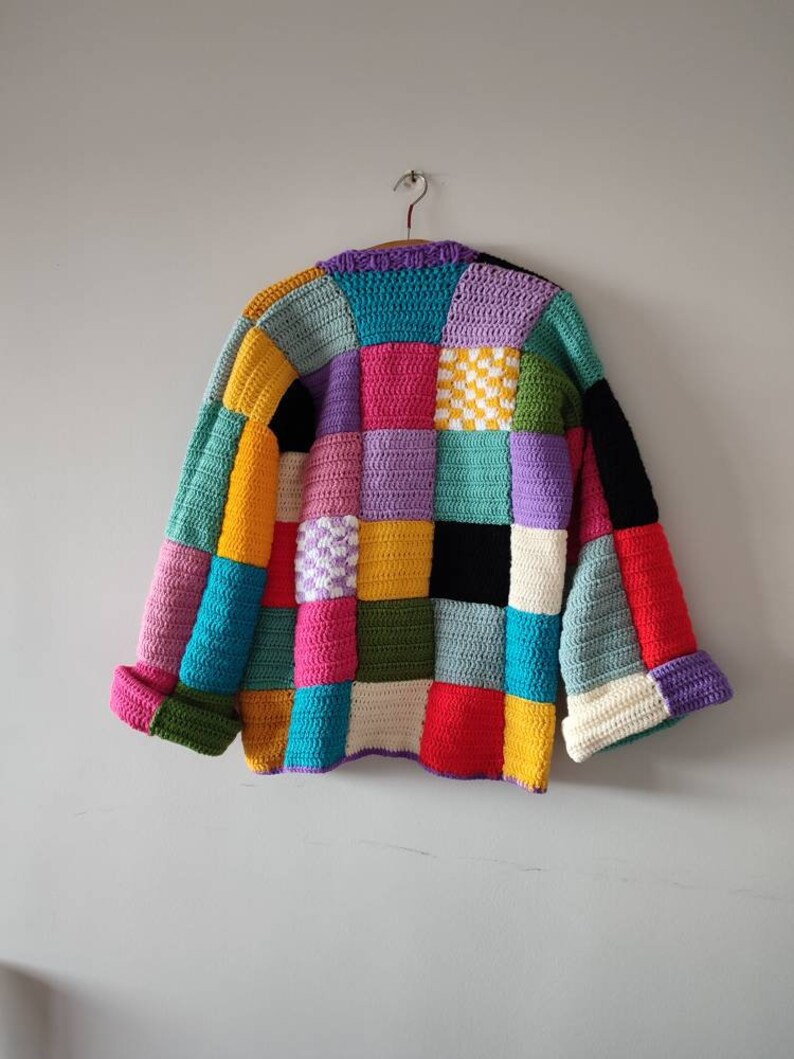Puede incluir: Un c&aacute;rdigan de crochet colorido con un dise&ntilde;o de patchwork. El c&aacute;rdigan est&aacute; hecho de cuadrados de varios colores, incluyendo rojo, amarillo, azul, verde, morado y blanco.