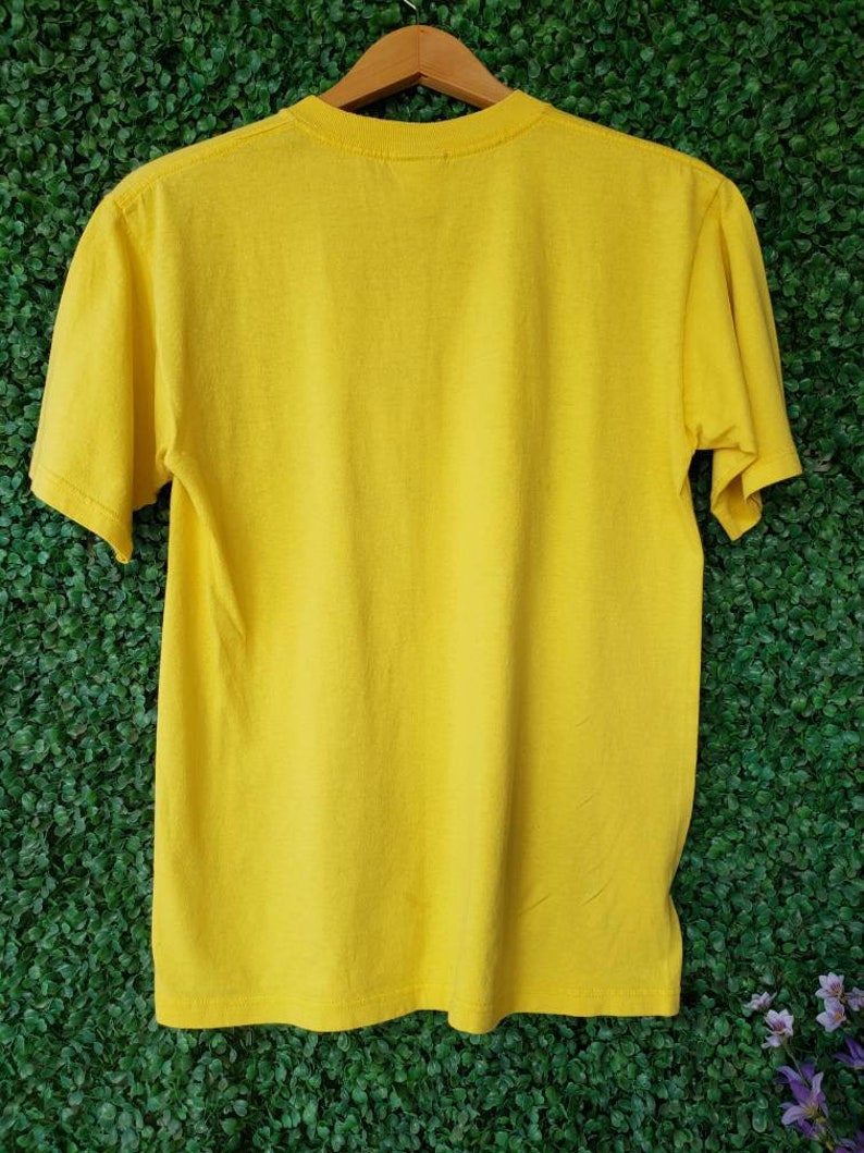 May include: A plain yellow short-sleeved t-shirt with a crew neck.