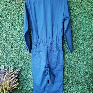 May include: A blue long-sleeved jumpsuit with a zipper closure and two pockets on the back.