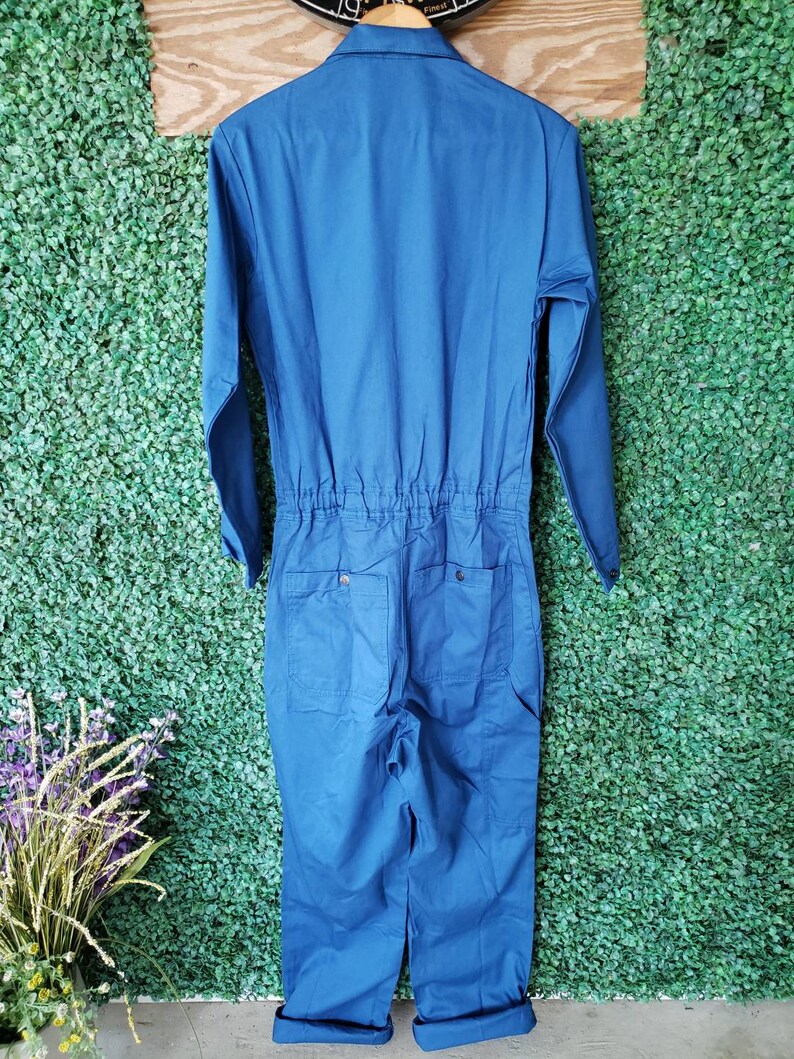 May include: A blue long-sleeved jumpsuit with a zipper closure and two pockets on the back.