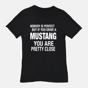 May include: Black t-shirt with white text that reads "Nobody is perfect but if you drive a Mustang you are pretty close."
