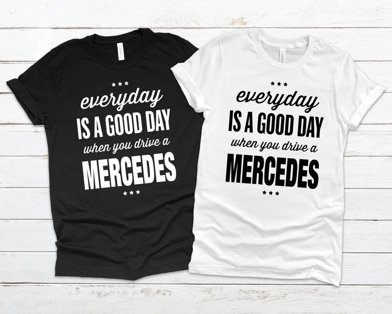 Op de afbeelding: Twee T-shirts met de tekst "*** everyday IS A GOOD DAY when you drive a MERCEDES ***" erop gedrukt. Een T-shirt is zwart en de andere is wit.