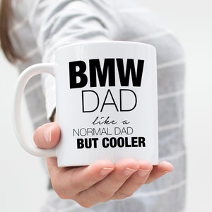 May include: White ceramic mug with a black design that reads "BMW DAD like a NORMAL DAD BUT COOLER".