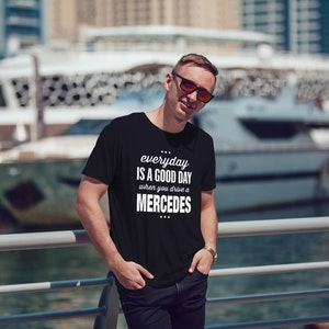 Op de afbeelding: Een zwart T-shirt met witte tekst die "everyday is a good day when you drive a MERCEDES" zegt.