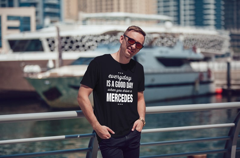 Op de afbeelding: Een zwart T-shirt met witte tekst die "everyday is a good day when you drive a MERCEDES" zegt.