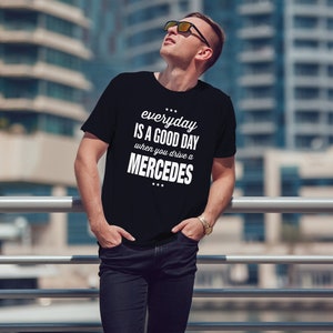 Op de afbeelding: Een zwart T-shirt met witte tekst die "everyday is a good day when you drive a MERCEDES" zegt.