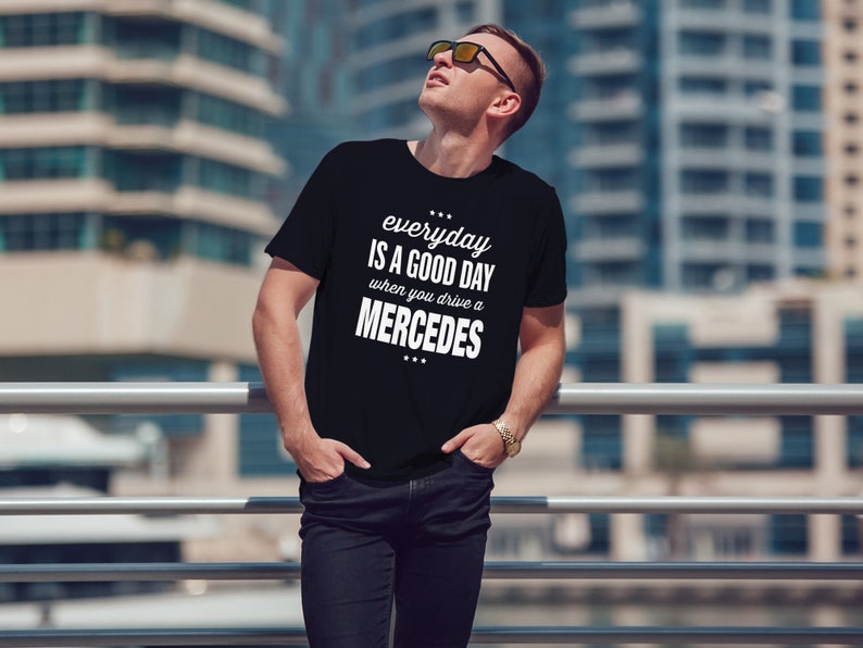Op de afbeelding: Een zwart T-shirt met witte tekst die "everyday is a good day when you drive a MERCEDES" zegt.