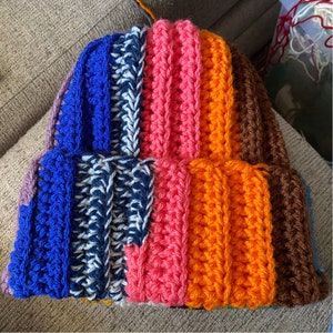May include: A colorful crocheted hat with stripes of blue, white, pink, orange, and brown.
