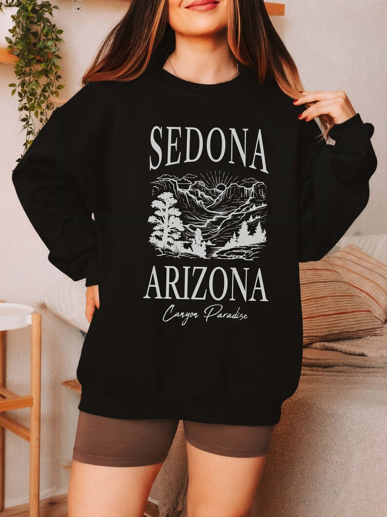 May include: Black sweatshirt with a white graphic design of a mountain landscape and the text "Sedona Arizona Canyon Paradise".