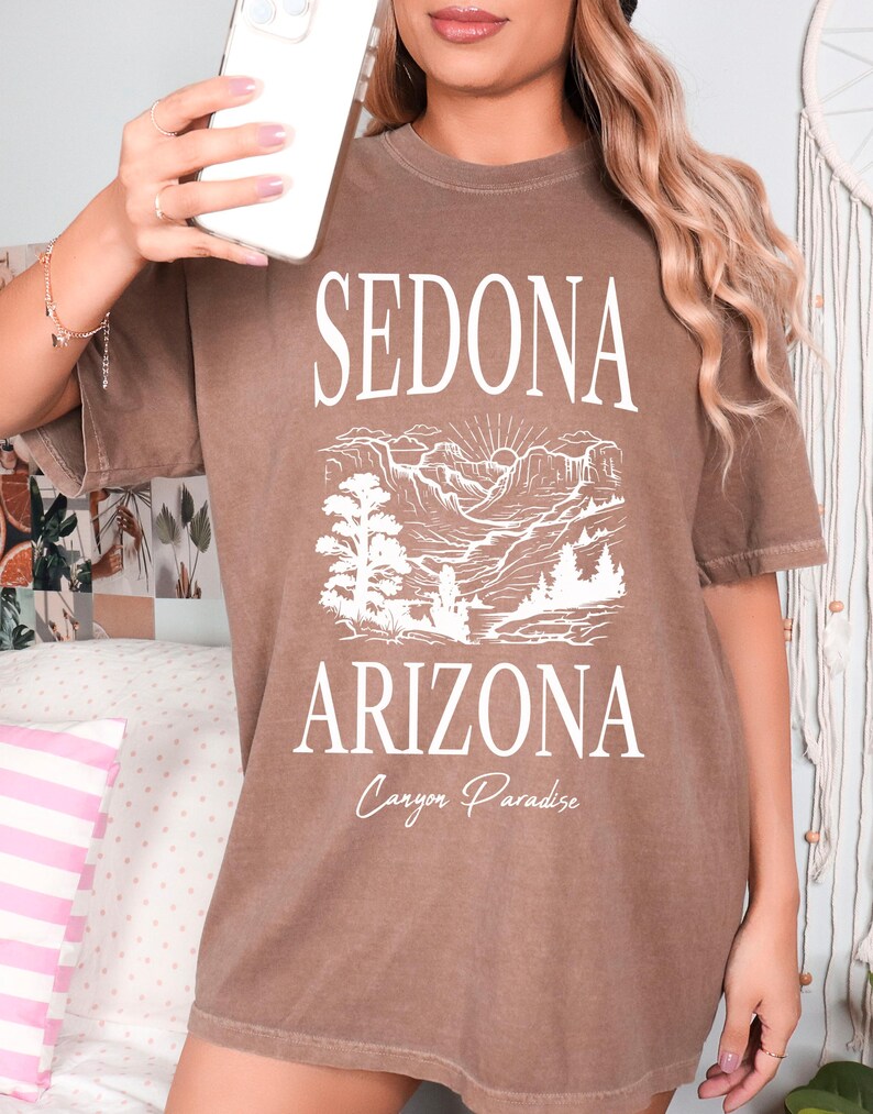 May include: A brown oversized t-shirt with a white graphic print of a mountain landscape and the text "Sedona Arizona Canyon Paradise".