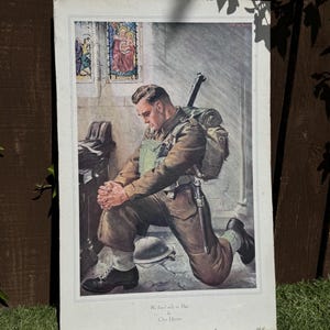 May include: A vintage print showing a soldier kneeling in prayer within a church setting. The soldier wears a military uniform, carrying a rifle and backpack. The print has a white border and includes the text "We kneel only to Thee" by Chris Upton.
