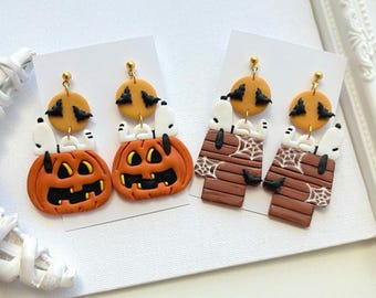 Puede incluir: Un par de pendientes con temática de Halloween. Un par presenta calabazas naranjas con figuras de Snoopy, y el otro par la caseta de Snoopy. Cada pendiente tiene un círculo amarillo con recortes de murciélagos negros.