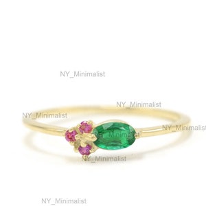 May include: A gold ring with a green oval gemstone and pink gemstones. The ring is simple and elegant.