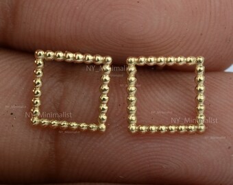 May include: A pair of gold square earrings with a beaded border. The earrings are small and delicate.