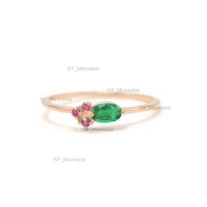 May include: A delicate gold ring with a green oval gemstone and pink gemstones. The ring is simple and elegant.