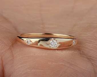 May include: A gold band ring with three small diamonds. The center diamond is larger than the two diamonds on either side.