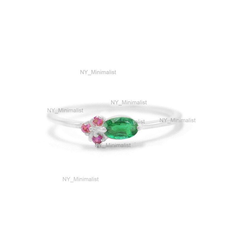 May include: A silver ring with a green oval gemstone and pink gemstones. The ring is on a white background.