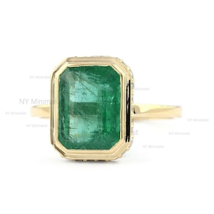 Anillo de compromiso de oro amarillo de 14 quilates con esmeralda zambiana tallada a mano y diamantes.
