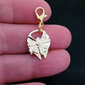 May include: A gold-colored charm featuring the Millennium Falcon spaceship design. The charm is attached to a gold-colored lobster clasp. The spaceship has detailed paneling and a distinctive shape, perfect for a Star Wars fan.