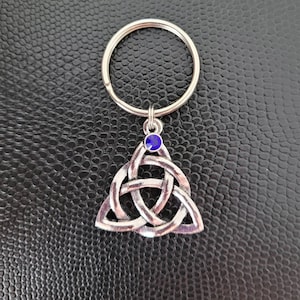 May include: Silver key chain with a blue crystal and a Celtic knot design.