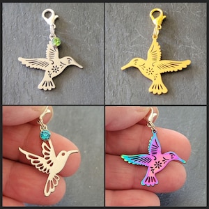May include: Four hummingbird charms with different coloured finishes. The charms are made of metal and feature a detailed hummingbird design. Each charm has a small crystal attached to the top.
