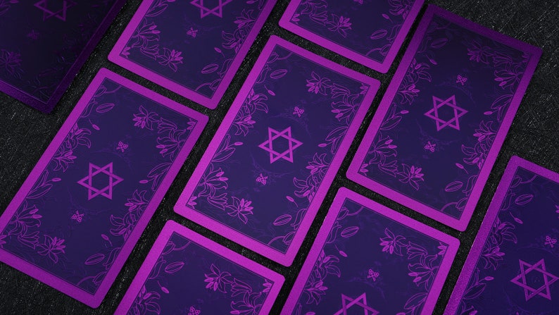 Pu&ograve; includere: Un set di carte dei tarocchi con un design viola e nero. Le carte presentano una stella di David e motivi floreali.