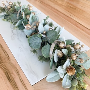 May include: A green and gold garland with silver rings, perfect for a holiday table centerpiece.