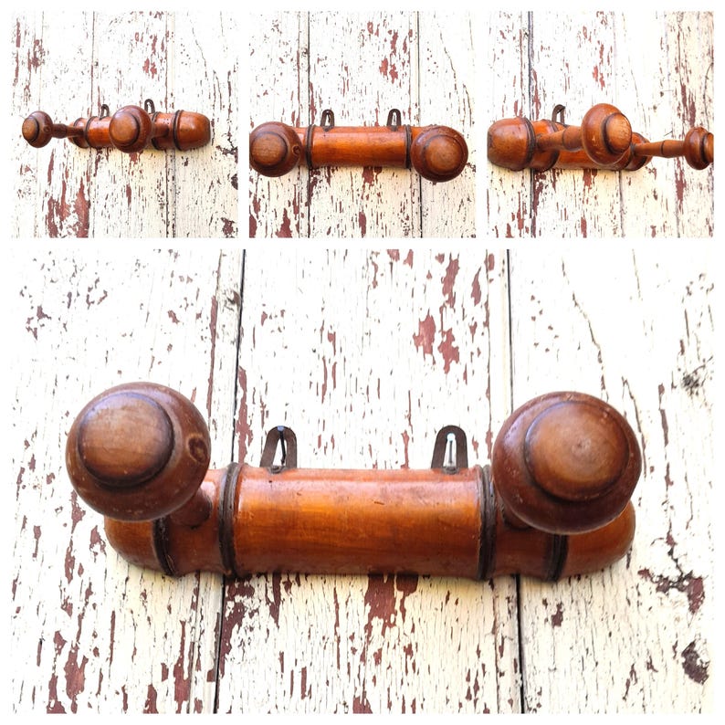 May include: A wooden coat rack with three hooks and rounded ends. The rack is made of a light brown wood and has a natural finish.