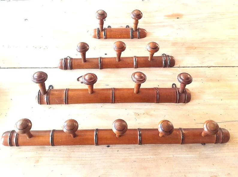 May include: Four wooden coat racks made of bamboo with round wooden knobs. The racks are stacked on top of each other, with the top rack having two knobs, the second rack having three knobs, the third rack having five knobs, and the bottom rack having five knobs.