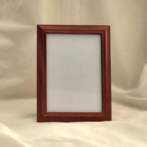May include: A dark brown wooden picture frame with a white mat and a clear glass front.