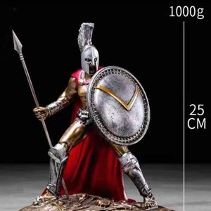 Könnte beinhalten: Detaillierte Figur eines spartanischen Kriegers, der einen Speer und einen Schild hält. Die Figur ist in silberner und goldener Rüstung mit einem roten Umhang gekleidet. Der Schild hat einen goldenen Akzent. Die Figur ist 25 cm hoch und wiegt 1000g.