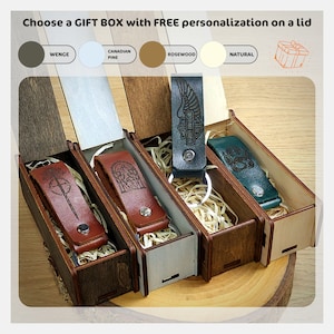 May include: Four wooden gift boxes with lids, each containing a leather keychain with a different design. The boxes are made of different wood types: wenge, Canadian pine, rosewood, and natural. The keychains feature a sword, a tree, a Harley Davidson logo, and a paw print.