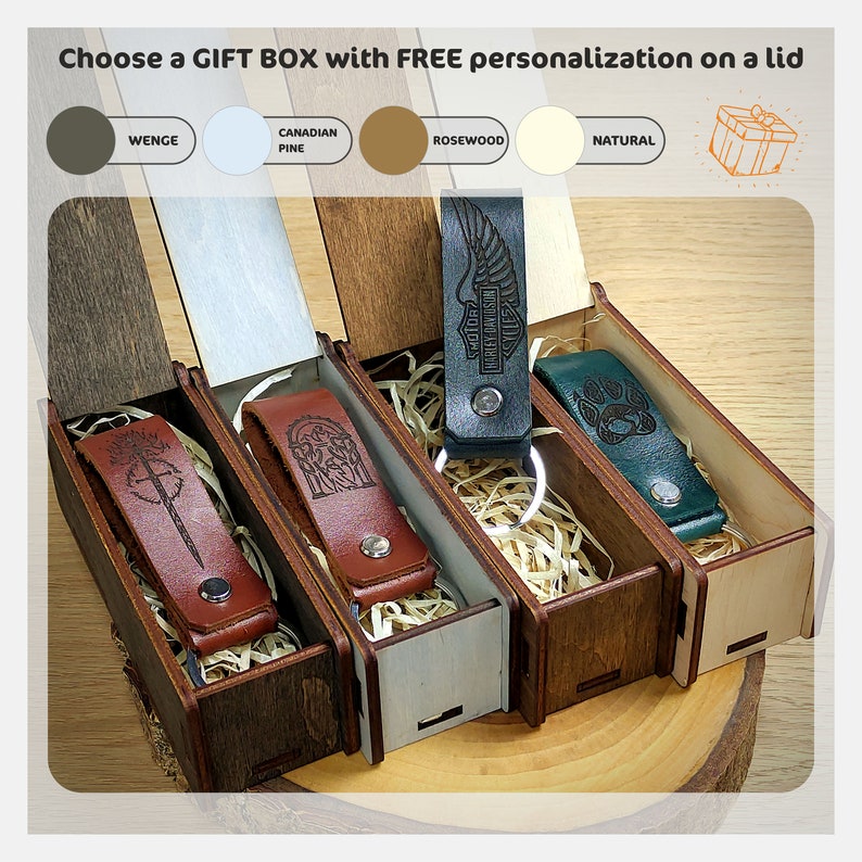 May include: Four wooden gift boxes with lids, each containing a leather keychain with a different design. The boxes are made of different wood types: wenge, Canadian pine, rosewood, and natural. The keychains feature a sword, a tree, a Harley Davidson logo, and a paw print.