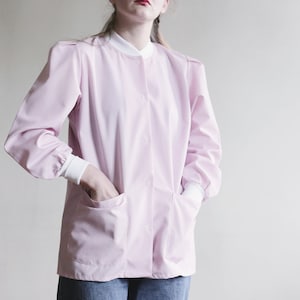 May include: A pink button-up shirt with long sleeves and two pockets. The shirt has a white collar and cuffs.