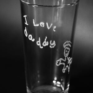 May include: A clear glass with the words "I love daddy" written on it in white marker. A simple stick figure drawing is also visible on the glass.