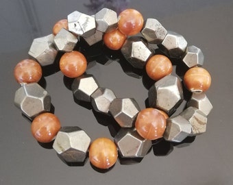 May include: A bracelet made of brown wooden beads and silver metal beads. The beads are faceted and have a geometric shape.