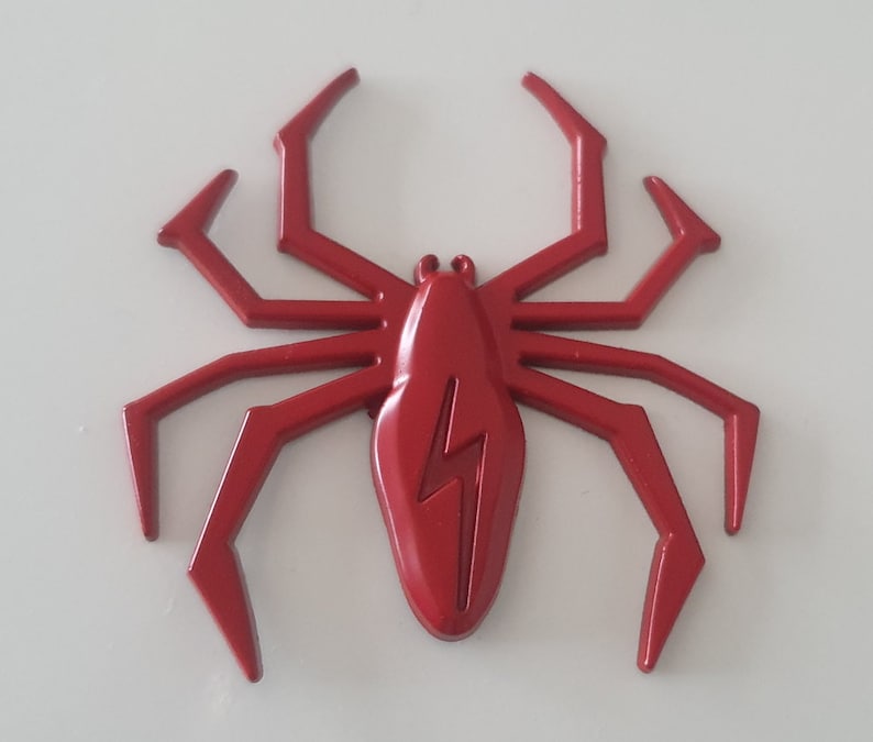 May include: A red plastic spider with a lightning bolt design on its body. The spider has eight legs and is a decorative item.