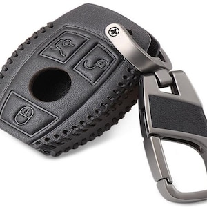May include: Black leather key fob with a stitched design and a silver metal key ring. The key fob has four buttons and a small hole in the center.