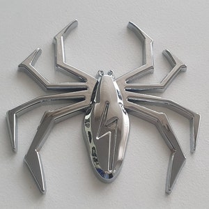 May include: A chrome-plated spider with a lightning bolt design on its body. The spider has eight legs and is a decorative item.